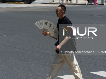 People are walking across the street during the heatwave in Shanghai, China, on July 4, 2024, as the temperature reaches 39 degrees Celsius...