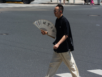 People are walking across the street during the heatwave in Shanghai, China, on July 4, 2024, as the temperature reaches 39 degrees Celsius...