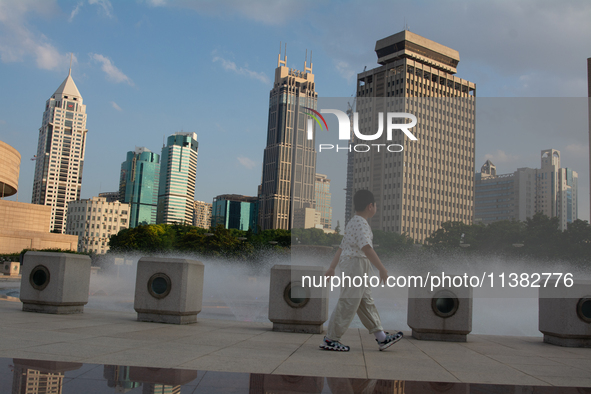 A boy is walking next to the water fountain in the People's Square in Shanghai, China, on July 4, 2024, as the temperature reaches 39 degree...