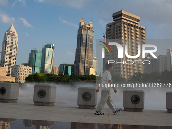 A boy is walking next to the water fountain in the People's Square in Shanghai, China, on July 4, 2024, as the temperature reaches 39 degree...