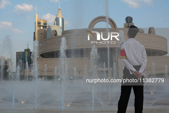 A security worker is standing next to the water fountain in People's Square in Shanghai, China, on July 4, 2024, as the temperature is reach...