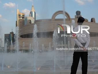 A security worker is standing next to the water fountain in People's Square in Shanghai, China, on July 4, 2024, as the temperature is reach...