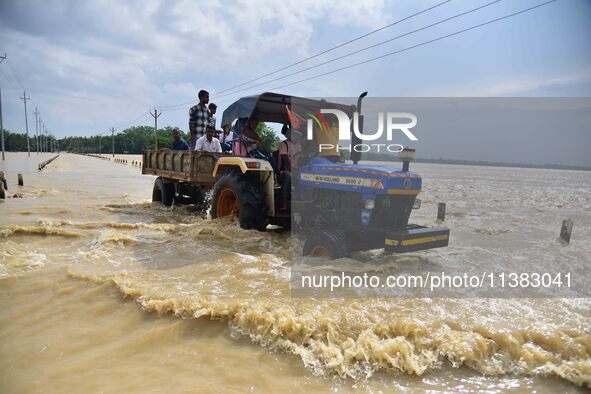 Villagers are crossing a flooded road on a tractor after heavy rainfall in Hojai District of Assam, India, on July 5, 2024. 