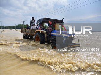 Villagers are crossing a flooded road on a tractor after heavy rainfall in Hojai District of Assam, India, on July 5, 2024. (