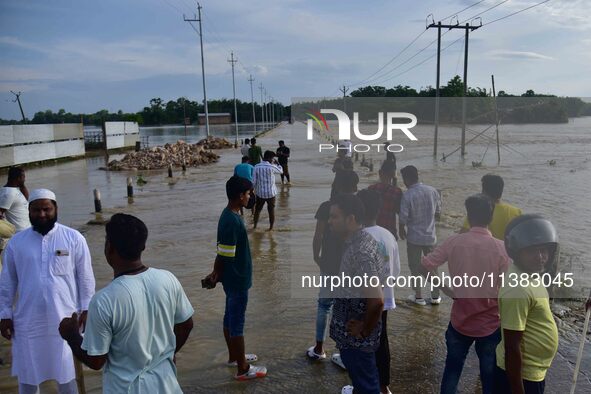 People are looking at a road submerged in flood water after heavy rainfall in Hojai District of Assam, India, on July 5, 2024. 