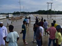 People are looking at a road submerged in flood water after heavy rainfall in Hojai District of Assam, India, on July 5, 2024. (