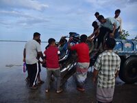 People are trying to load a bike onto a tractor to cross a flooded road after heavy rainfall in Hojai District of Assam, India, on July 5, 2...