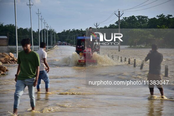 Villagers are crossing a flooded road on a tractor after heavy rainfall in Hojai District of Assam, India, on July 5, 2024. 