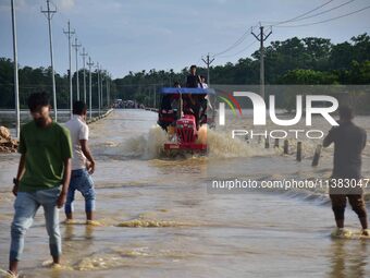 Villagers are crossing a flooded road on a tractor after heavy rainfall in Hojai District of Assam, India, on July 5, 2024. (