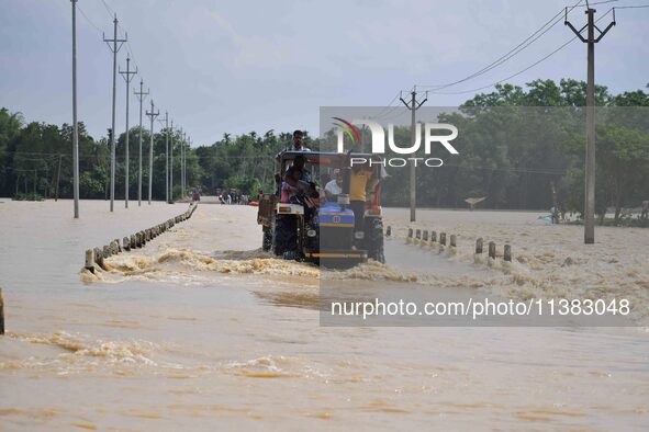 Villagers are crossing a flooded road on a tractor after heavy rainfall in Hojai District of Assam, India, on July 5, 2024. 