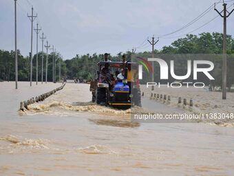 Villagers are crossing a flooded road on a tractor after heavy rainfall in Hojai District of Assam, India, on July 5, 2024. (