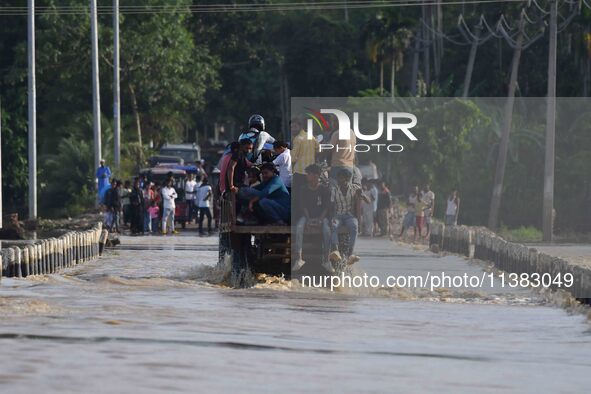 Villagers are crossing a flooded road on a tractor after heavy rainfall in Hojai District of Assam, India, on July 5, 2024. 