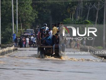 Villagers are crossing a flooded road on a tractor after heavy rainfall in Hojai District of Assam, India, on July 5, 2024. (