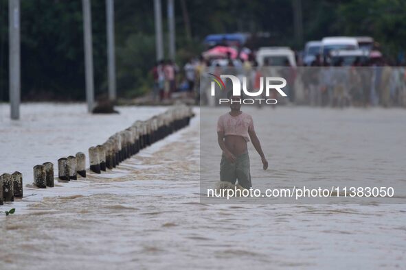 A villager is walking through a flooded road after heavy rainfall in Hojai District of Assam, India, on July 5, 2024. 