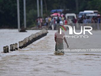 A villager is walking through a flooded road after heavy rainfall in Hojai District of Assam, India, on July 5, 2024. (