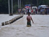 A villager is walking through a flooded road after heavy rainfall in Hojai District of Assam, India, on July 5, 2024. (