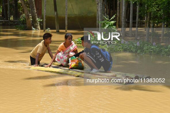 People are using a banana raft to cross a flooded area after heavy rainfall in Nagaon District of Assam, India, on July 5, 2024. 