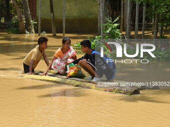 People are using a banana raft to cross a flooded area after heavy rainfall in Nagaon District of Assam, India, on July 5, 2024. (