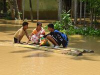 People are using a banana raft to cross a flooded area after heavy rainfall in Nagaon District of Assam, India, on July 5, 2024. (