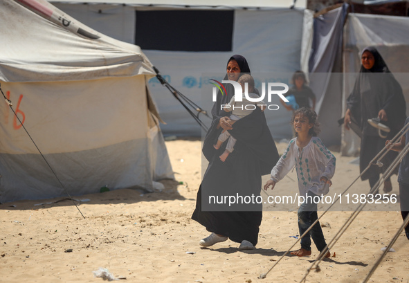 Displaced Palestinians are walking next to a temporary camp in Khan Yunis, south of the Gaza Strip, on July 4, 2024, amid the ongoing confli...