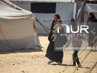 Displaced Palestinians are walking next to a temporary camp in Khan Yunis, south of the Gaza Strip, on July 4, 2024, amid the ongoing confli...