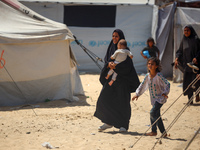 Displaced Palestinians are walking next to a temporary camp in Khan Yunis, south of the Gaza Strip, on July 4, 2024, amid the ongoing confli...