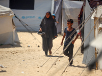 Displaced Palestinians are walking next to a temporary camp in Khan Yunis, south of the Gaza Strip, on July 4, 2024, amid the ongoing confli...