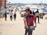 Displaced Palestinians are walking next to a temporary camp in Khan Yunis, south of the Gaza Strip, on July 4, 2024, amid the ongoing confli...