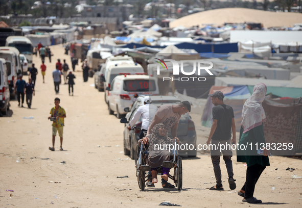 Displaced Palestinians are walking next to a temporary camp in Khan Yunis, south of the Gaza Strip, on July 4, 2024, amid the ongoing confli...