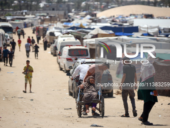 Displaced Palestinians are walking next to a temporary camp in Khan Yunis, south of the Gaza Strip, on July 4, 2024, amid the ongoing confli...