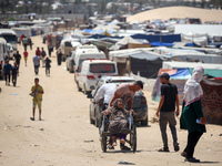 Displaced Palestinians are walking next to a temporary camp in Khan Yunis, south of the Gaza Strip, on July 4, 2024, amid the ongoing confli...