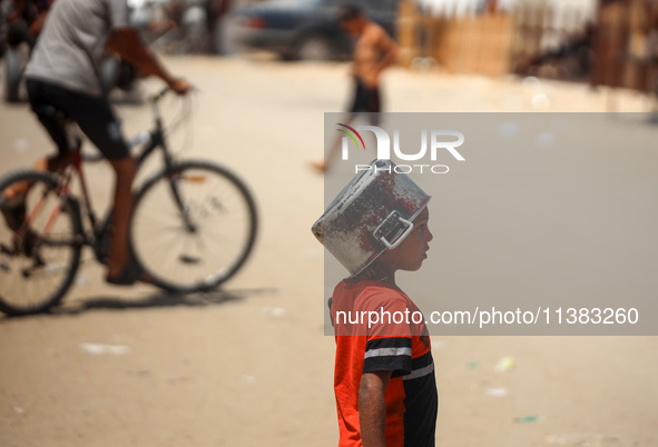 Displaced Palestinians are walking next to a temporary camp in Khan Yunis, south of the Gaza Strip, on July 4, 2024, amid the ongoing confli...