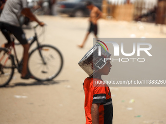 Displaced Palestinians are walking next to a temporary camp in Khan Yunis, south of the Gaza Strip, on July 4, 2024, amid the ongoing confli...