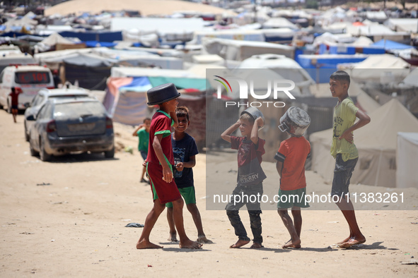 Displaced Palestinians are walking next to a temporary camp in Khan Yunis, south of the Gaza Strip, on July 4, 2024, amid the ongoing confli...