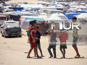 Displaced Palestinians are walking next to a temporary camp in Khan Yunis, south of the Gaza Strip, on July 4, 2024, amid the ongoing confli...