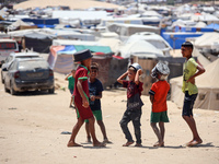 Displaced Palestinians are walking next to a temporary camp in Khan Yunis, south of the Gaza Strip, on July 4, 2024, amid the ongoing confli...