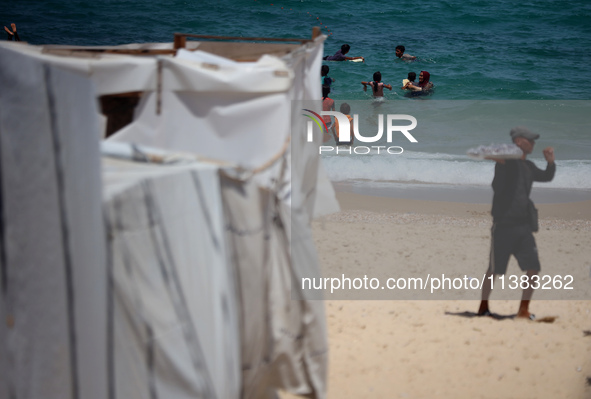 Displaced Palestinians are swimming next to a temporary camp in Khan Yunis, south of the Gaza Strip, on July 4, 2024, amid the ongoing confl...