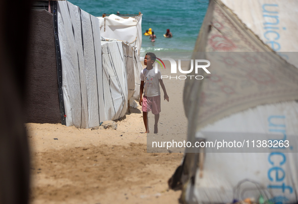 Displaced Palestinians are walking next to a temporary camp in Khan Yunis, south of the Gaza Strip, on July 4, 2024, amid the ongoing confli...