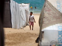 Displaced Palestinians are walking next to a temporary camp in Khan Yunis, south of the Gaza Strip, on July 4, 2024, amid the ongoing confli...