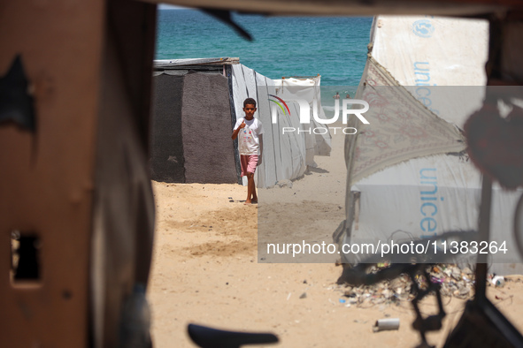 Displaced Palestinians are walking next to a temporary camp in Khan Yunis, south of the Gaza Strip, on July 4, 2024, amid the ongoing confli...