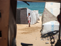 Displaced Palestinians are walking next to a temporary camp in Khan Yunis, south of the Gaza Strip, on July 4, 2024, amid the ongoing confli...