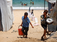 Displaced Palestinians are walking next to a temporary camp in Khan Yunis, south of the Gaza Strip, on July 4, 2024, amid the ongoing confli...