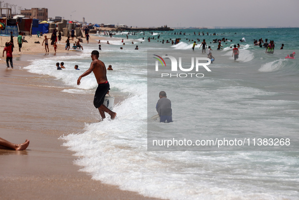 Displaced Palestinians are swimming next to a temporary camp in Khan Yunis, south of the Gaza Strip, on July 4, 2024, amid the ongoing confl...