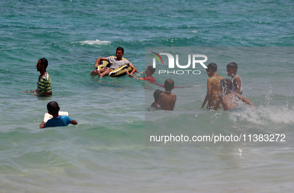 Displaced Palestinians are swimming next to a temporary camp in Khan Yunis, south of the Gaza Strip, on July 4, 2024, amid the ongoing confl...