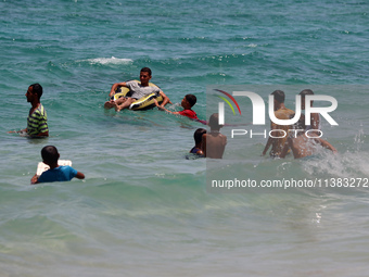 Displaced Palestinians are swimming next to a temporary camp in Khan Yunis, south of the Gaza Strip, on July 4, 2024, amid the ongoing confl...