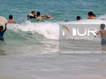 Displaced Palestinians are swimming next to a temporary camp in Khan Yunis, south of the Gaza Strip, on July 4, 2024, amid the ongoing confl...