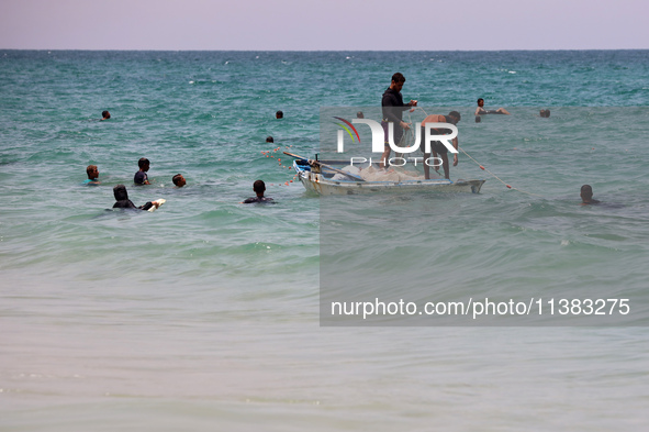 Displaced Palestinians are swimming next to a temporary camp in Khan Yunis, south of the Gaza Strip, on July 4, 2024, amid the ongoing confl...