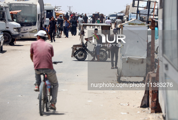 Displaced Palestinians are walking next to a temporary camp in Khan Yunis, south of the Gaza Strip, on July 4, 2024, amid the ongoing confli...