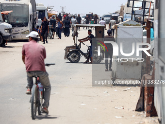 Displaced Palestinians are walking next to a temporary camp in Khan Yunis, south of the Gaza Strip, on July 4, 2024, amid the ongoing confli...