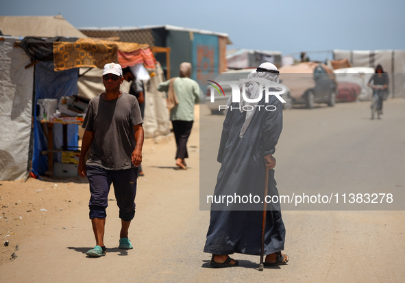 Displaced Palestinians are walking next to a temporary camp in Khan Yunis, south of the Gaza Strip, on July 4, 2024, amid the ongoing confli...